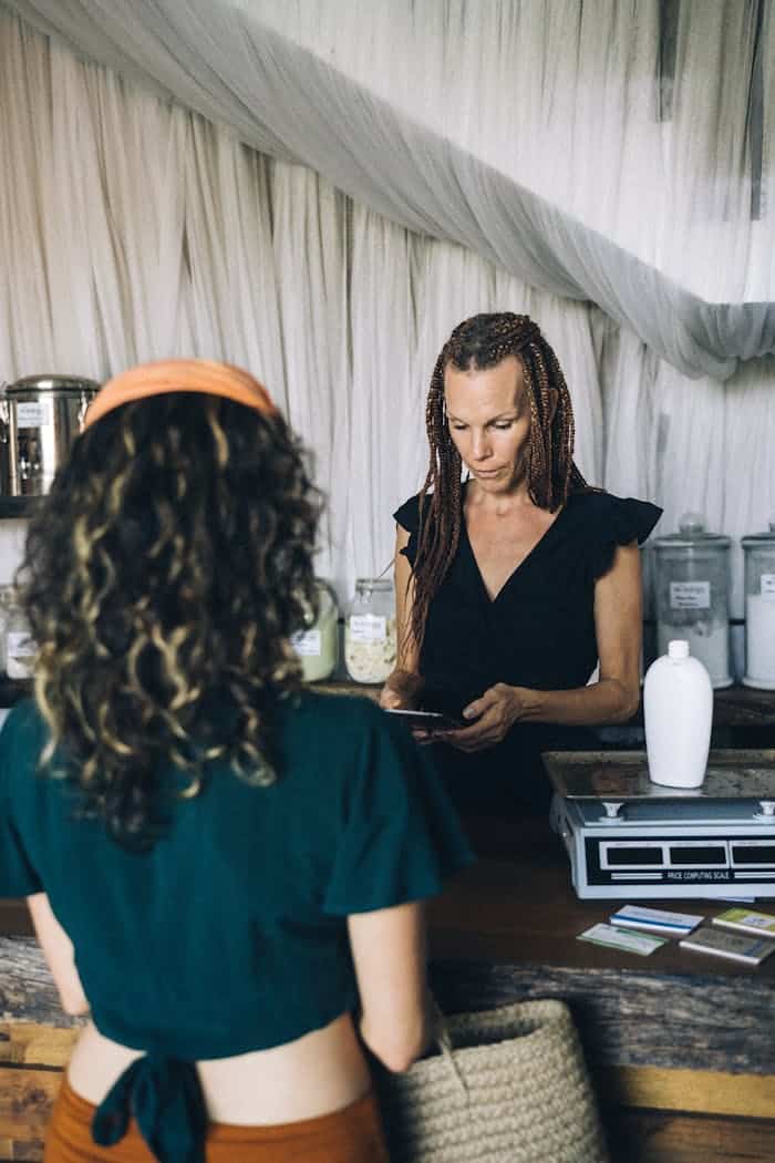 services-03 A woman completes a transaction at a boutique store's counter, interacting with a customer.