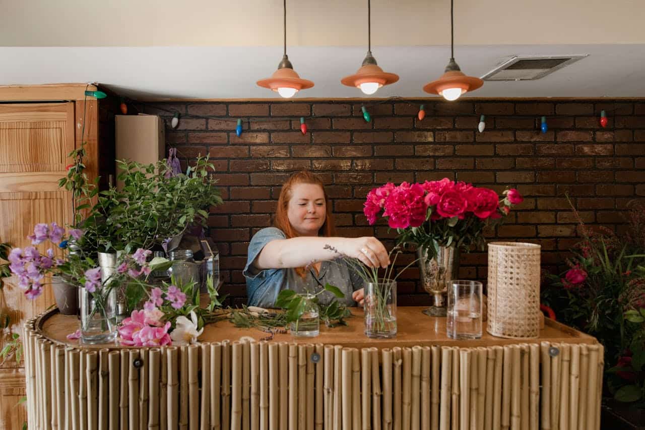 about-01 A female florist arranging a vibrant bouquet in an indoor floral shop setting.