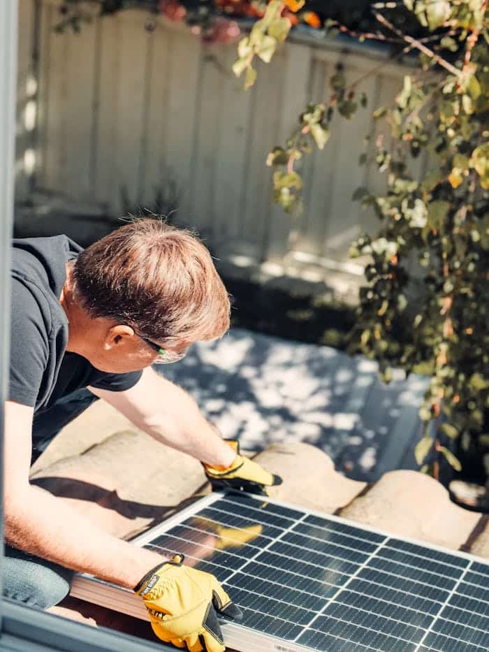 gallery-3 An adult male installing a solar panel on a rooftop, highlighting clean energy technology.
